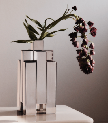 Sculpturale vaas van gepolijst roestvrij staal van Ferm Living met donkerrode bloemen